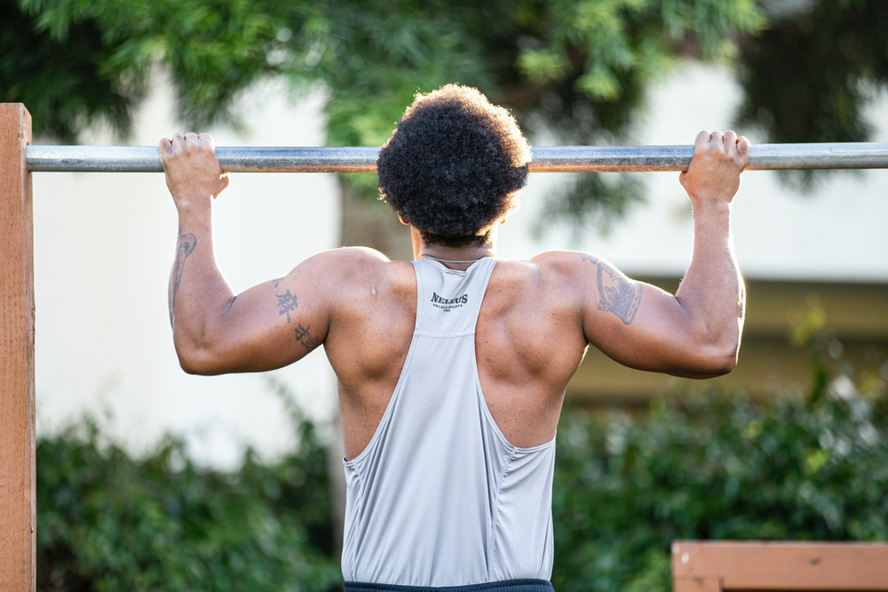 Focused male athlete demonstrating strength with a precise pull-up, showcasing proper form and determination in fitness training.