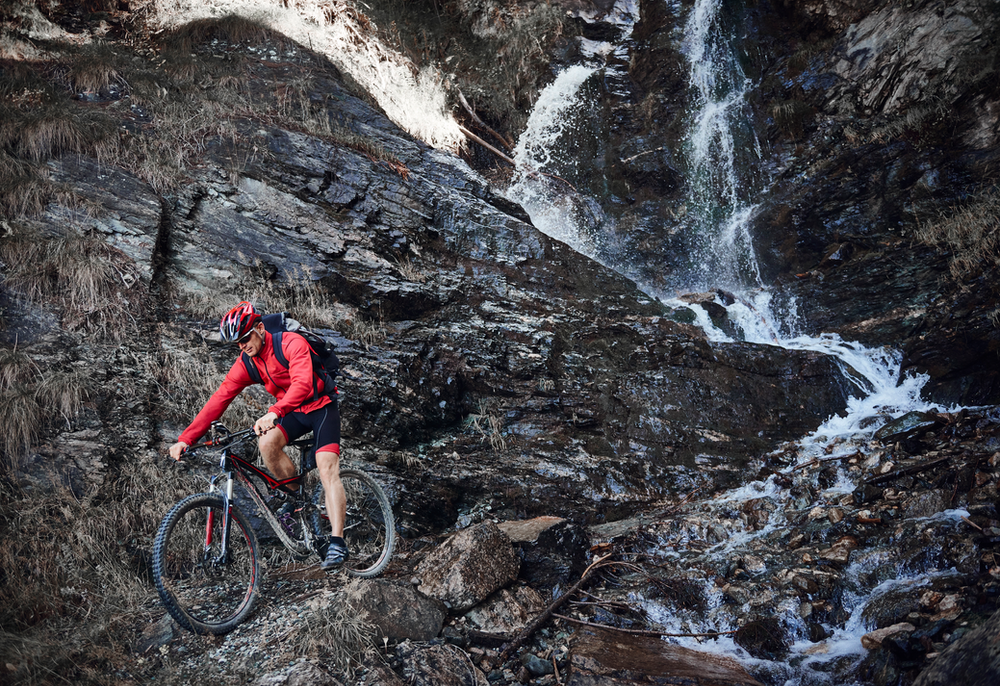 man mountain biking near a waterfall