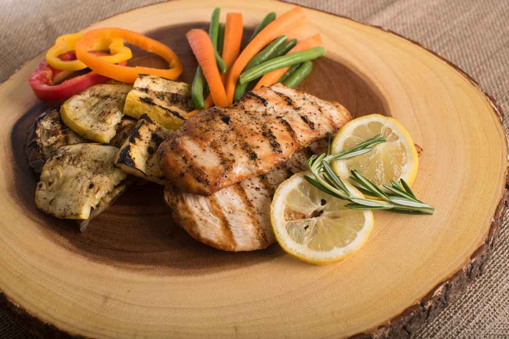 a plate of grilled chicken and assorted colorful vegetables, a balanced and nutritious meal on a table