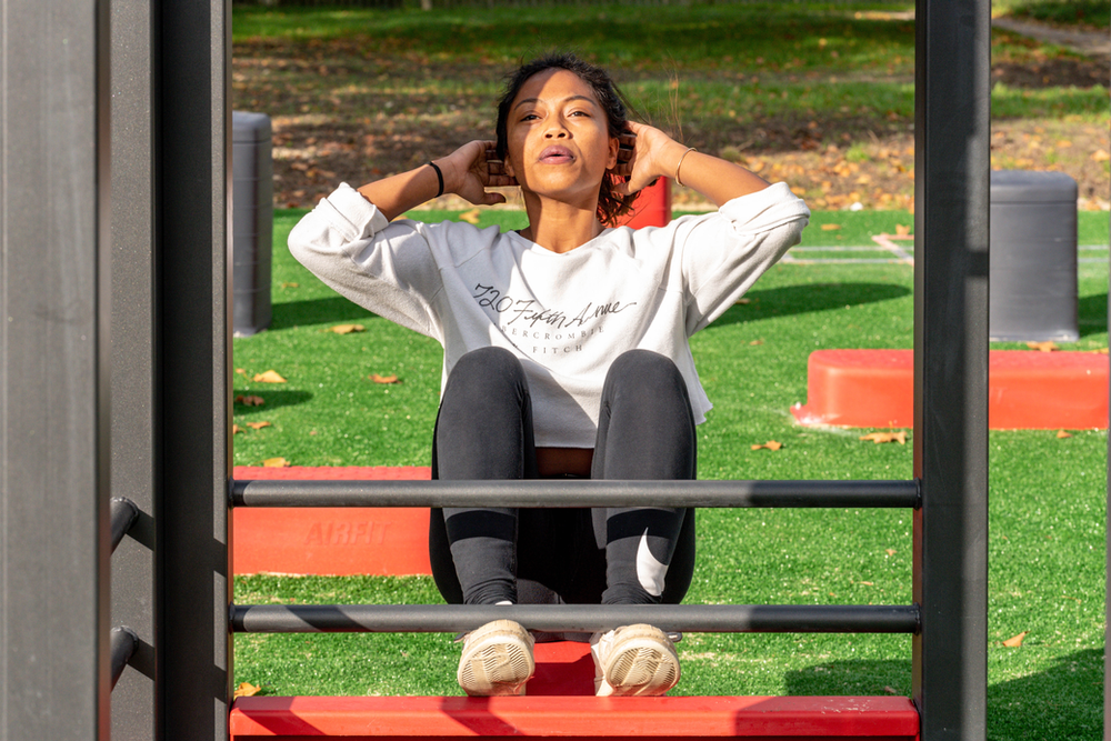 a woman doing crunches outdoors on a mat, showcasing abdominal exercises in an outdoor fitness setting