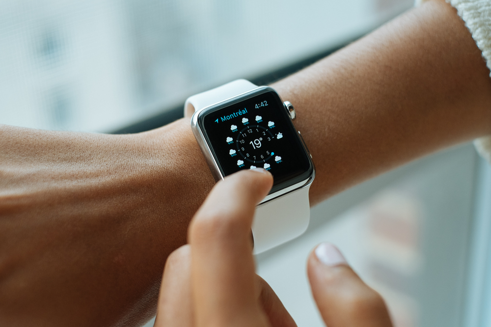 A woman wearing a smartwatch on her wrist, seamlessly blending technology with style. The smartwatch features a sleek design, and the woman appears engaged with its display, highlighting the integration of modern wearable technology into daily life