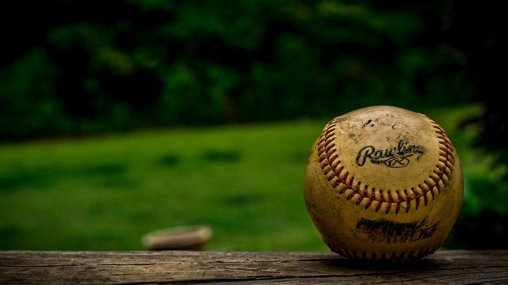 Baseball resting on the field, bathed in sunlight, capturing the anticipation of the game about to unfold