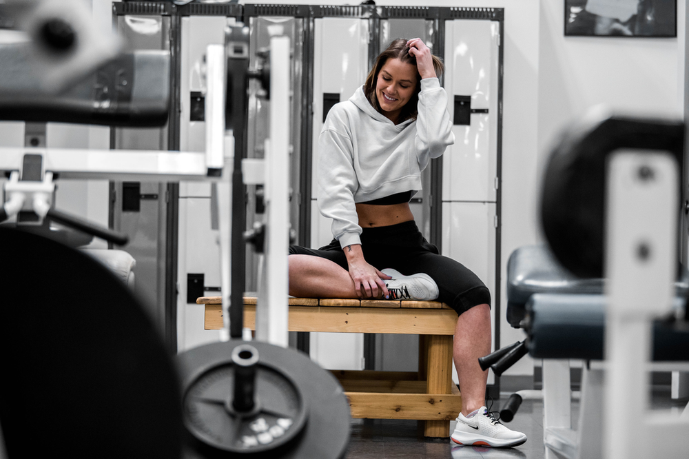 woman sitting on a bench next to a power rack