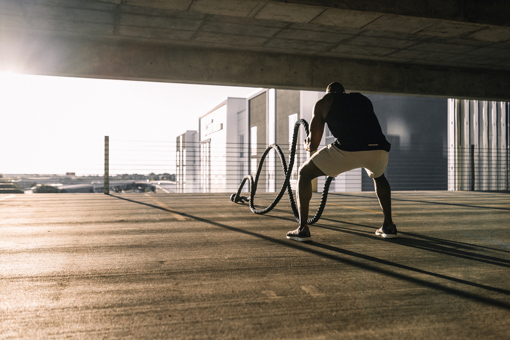 man using a battle rope outside to build muscle
