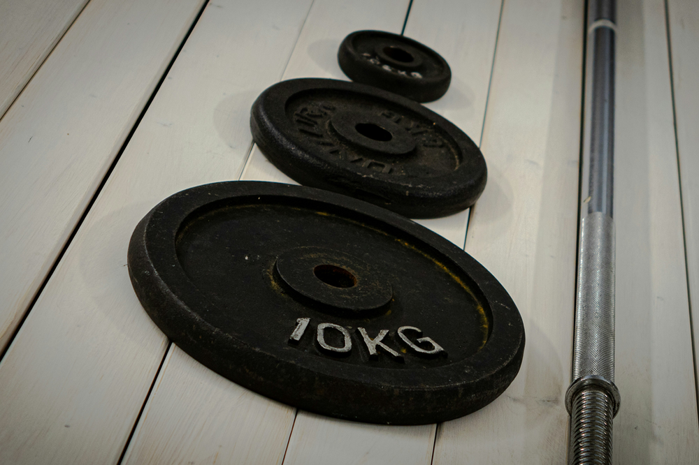 bumper weight plates, varying in size and weight, arranged neatly on the floor. The rubber-coated plates are labeled with weight indications and feature a 2-inch center hole, suitable for Olympic barbells. The textured surface and vibrant colors highlight their durability and versatility for weightlifting workouts.