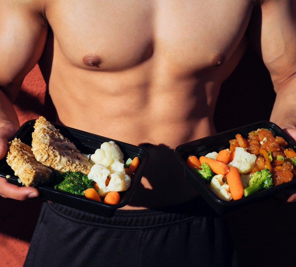 After an intense workout, a man proudly displays quality protein dishes. The image showcases a selection of nutritious post-workout meals, highlighting the importance of protein for muscle recovery.