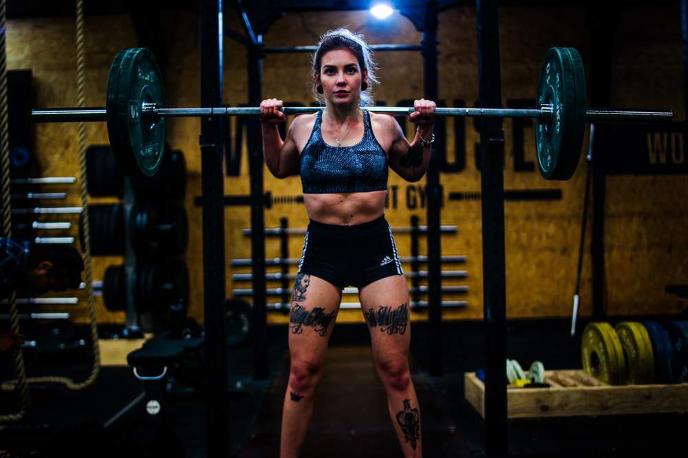 Woman lifting weights in a gym, showcasing strength and determination. Gym equipment in the background, creating a fitness-focused environment. Empowering image of a woman engaged in weightlifting, promoting a healthy and active lifestyle