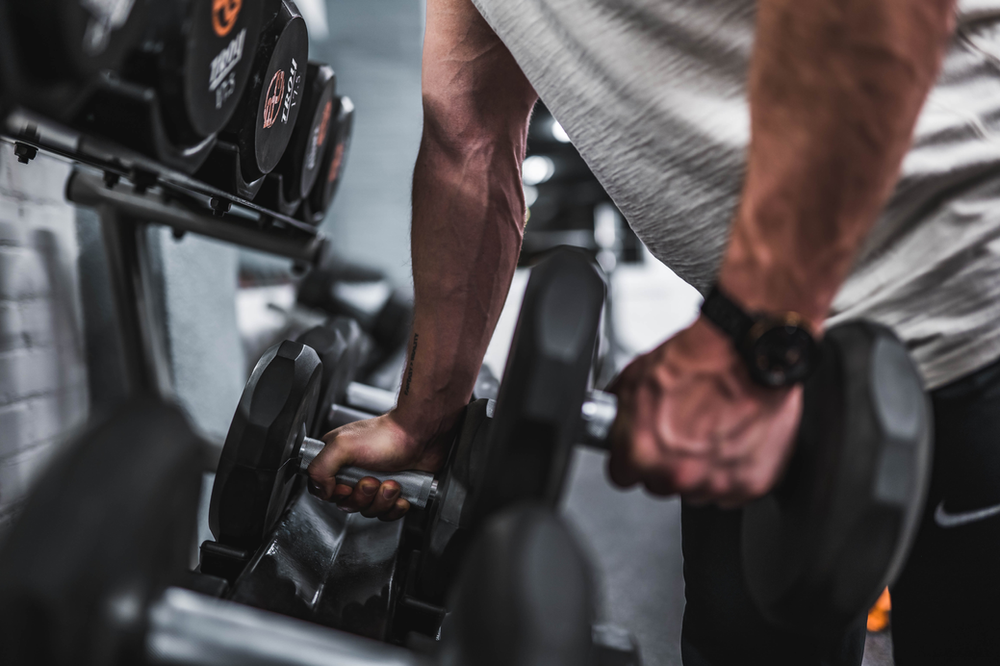 Man lifting handweights, demonstrating strength and fitness. Focused on weightlifting exercise with handheld weights. Determination and commitment to a healthy lifestyle showcased in the image.