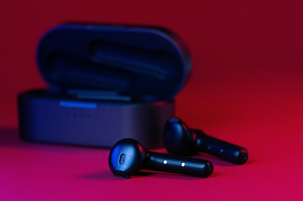 Earbuds in their protective case placed on a table, showcasing sleek design and portability